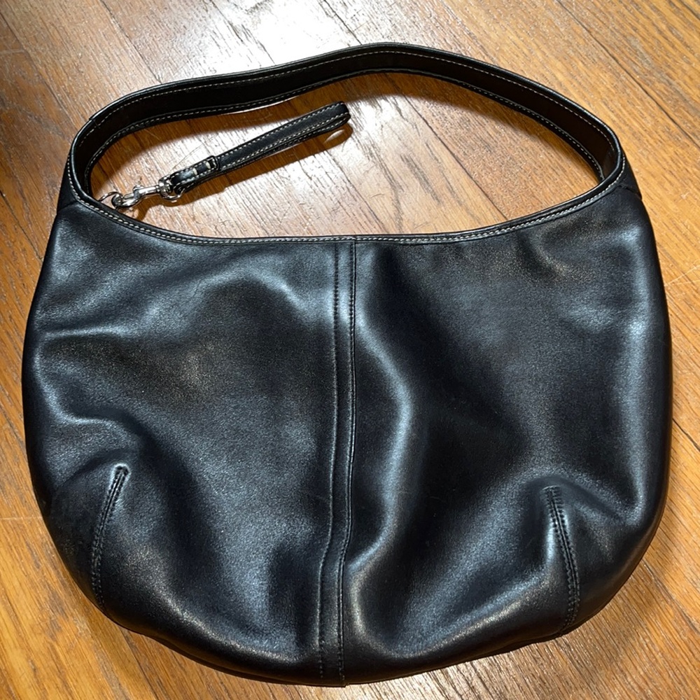 Coach black leather bag with zip closure .